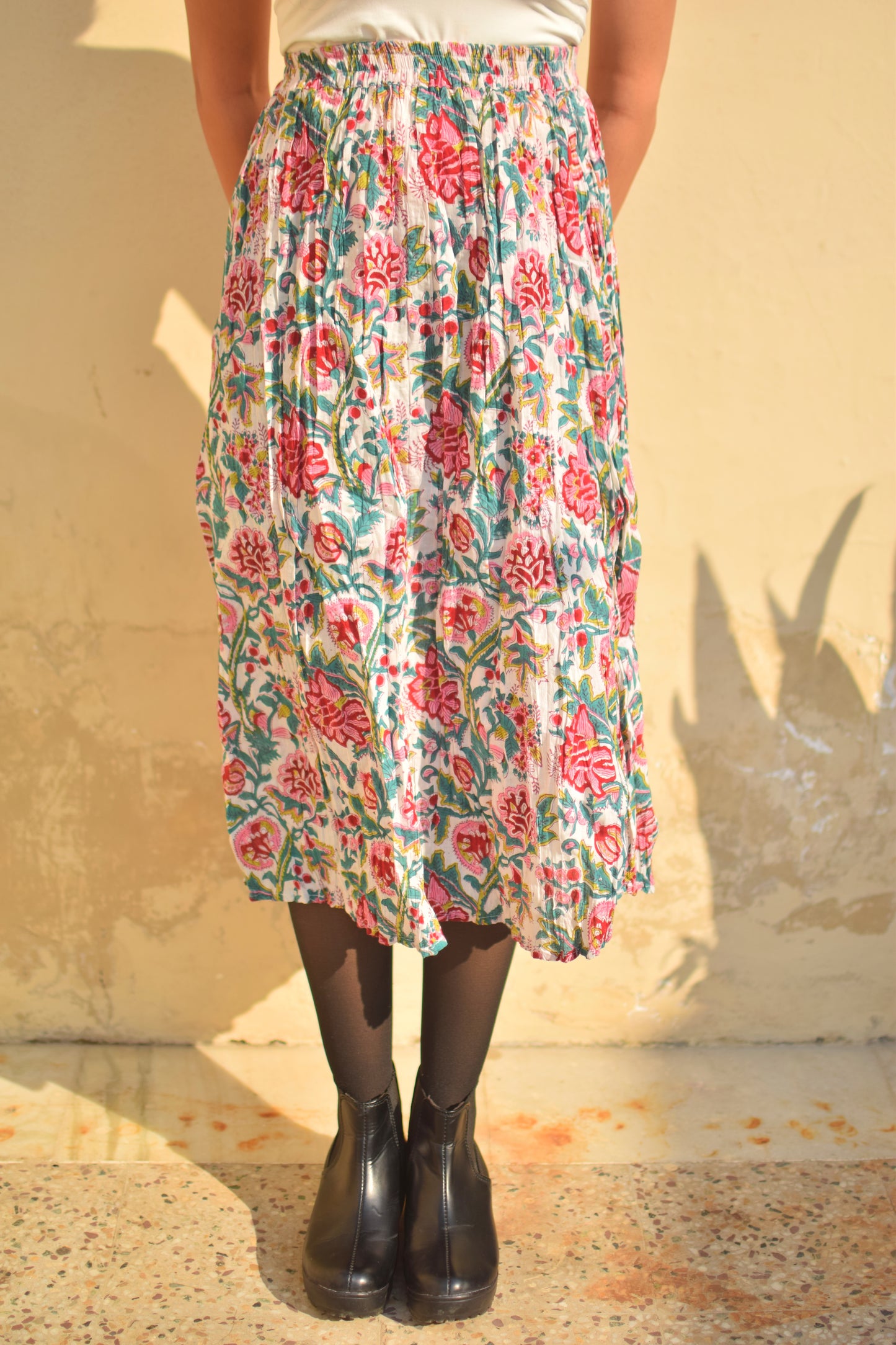 Person wearing a floral skirt with a plain background