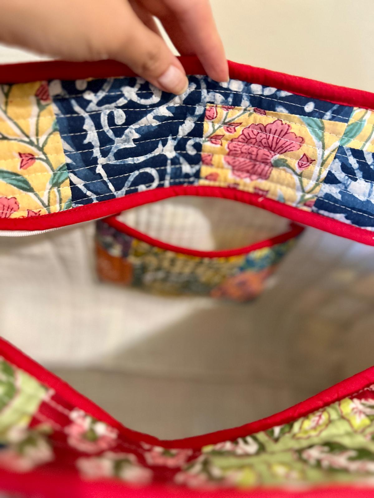 Close-up of a colorful quilted hand block printed fabric tote bag with floral patterns and red borders.
