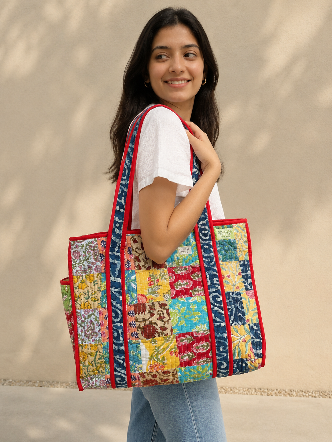 Woman holding a colorful quilted bag against a beige background
