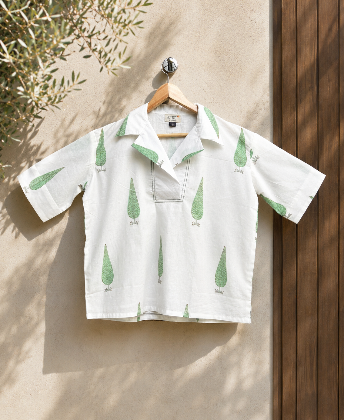 White green cypress shirt hanging on a beige wall outdoor.
