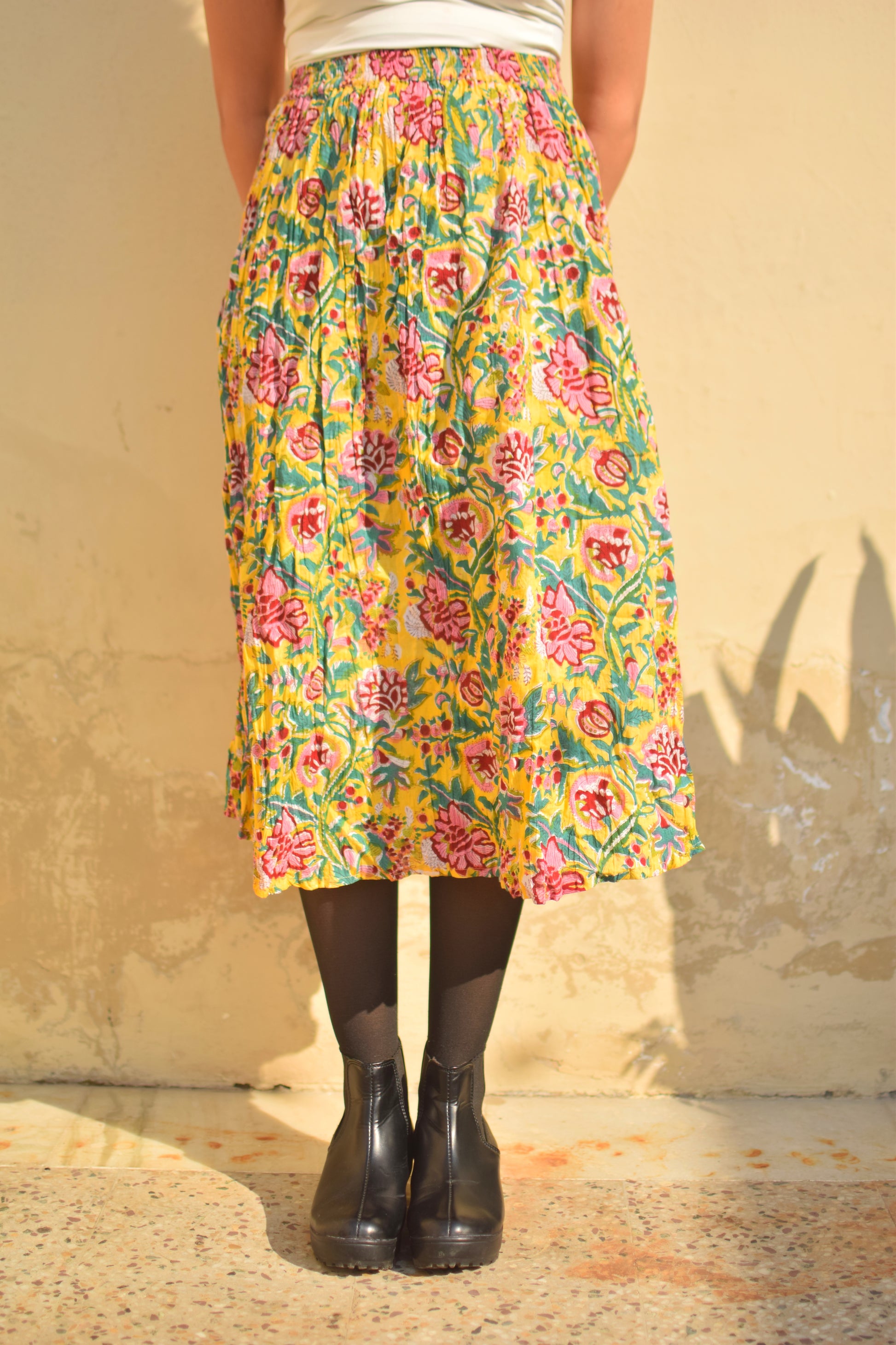 Person wearing a colorful floral skirt with a plain background