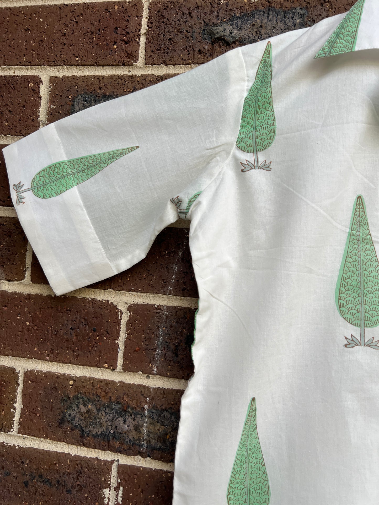 White fabric top sleeve with green leaf patterns draped over a brick surface