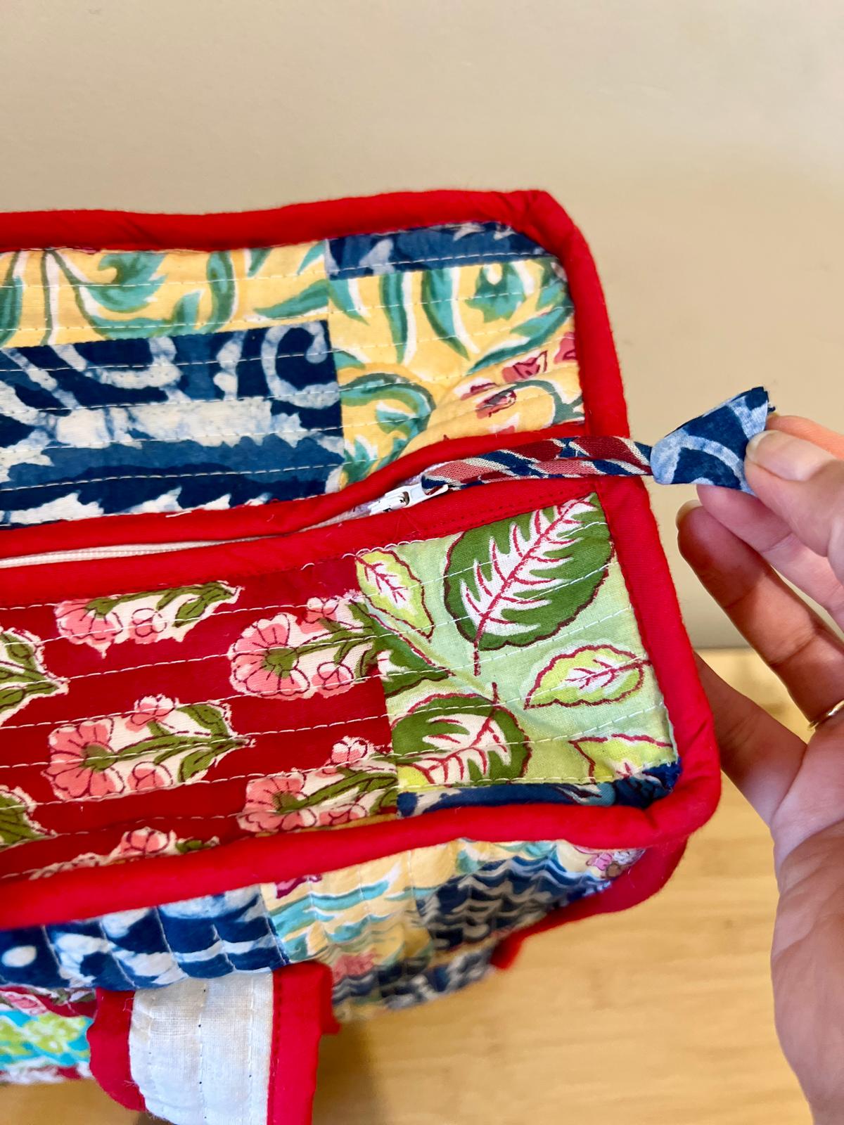 Colorful fabric tote bag with floral patterns held by a hand on a wooden surface.