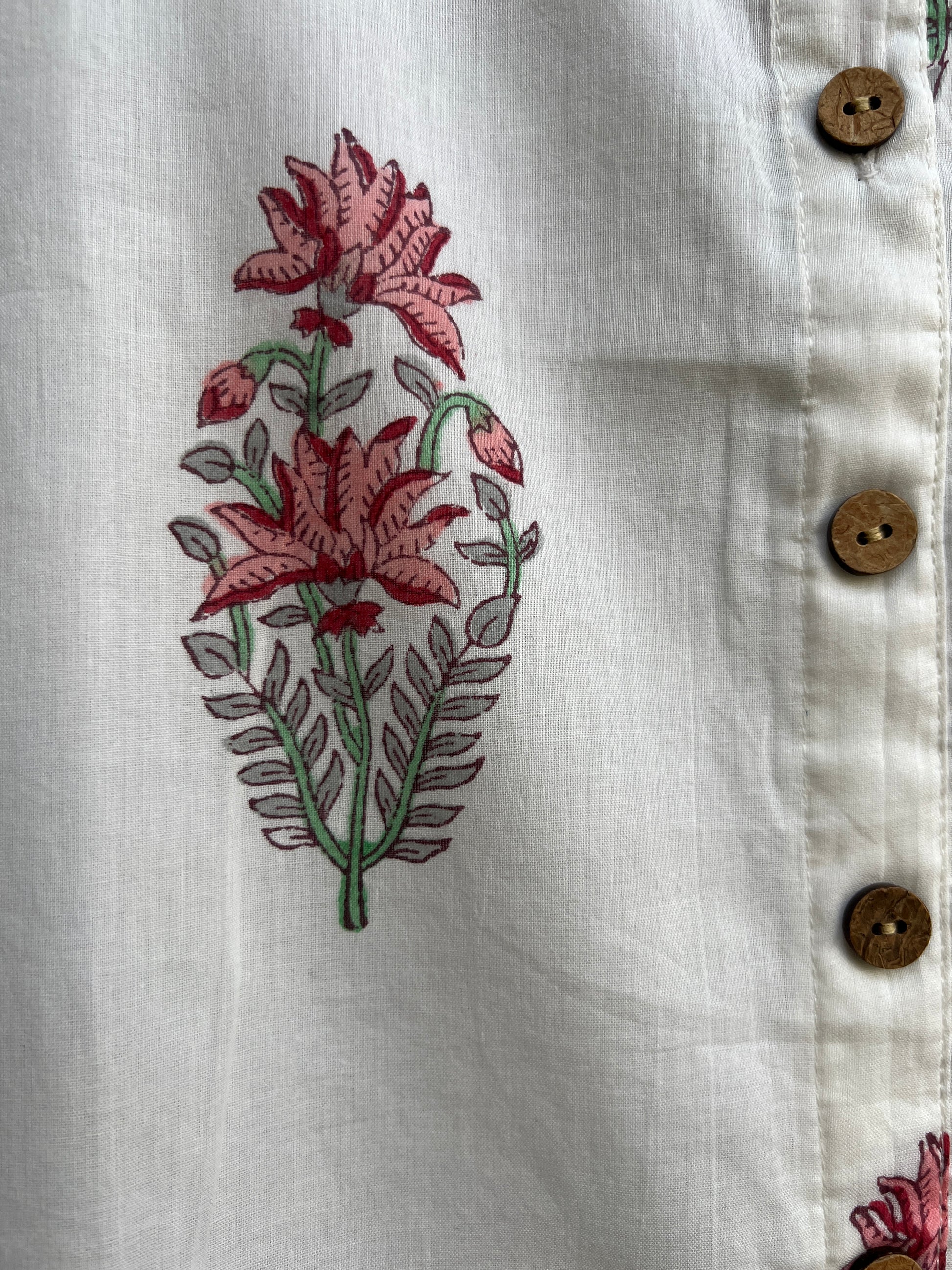 Close-up of a white lounge top with a pink and green floral print and four brown buttons along the top edge.