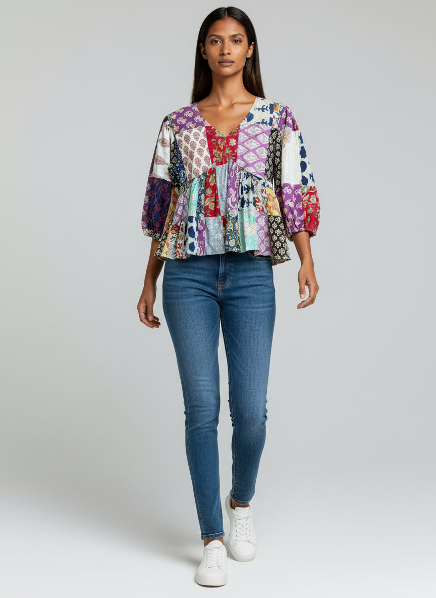 Woman wearing a colorful patchwork blouse and blue jeans on a white background
